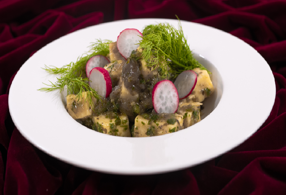 Photo d'un plat de présentation : cubes de fromage, avec sauce et radis par-dessus.