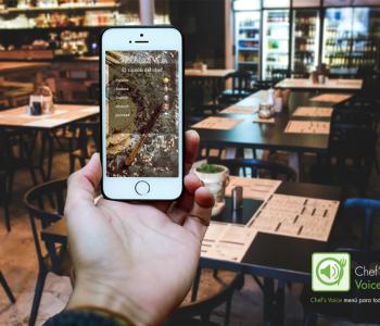 Imagen de un teléfono con Chef&#039;s Voice frente a las mesas de comedor de un colegio