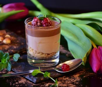 vaso de chocolate con frutos del bosque sobre mesa decorada con flores y chocolate