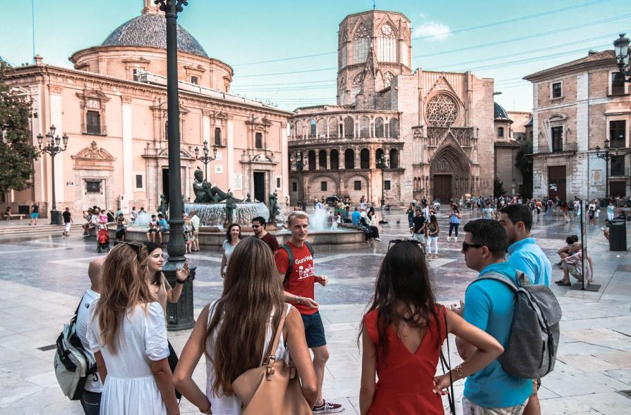día del guía de turismo Grupo de personas jóvenes en una plaza, escuchando a su guía turístico